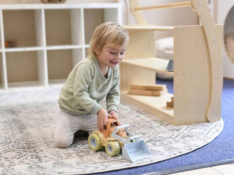 A kid is playing with a truck toy inside Little Jasper Centre