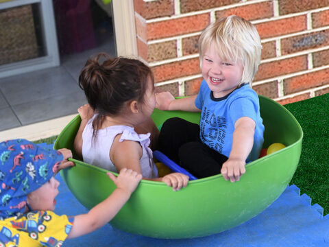 Three kids are playing while a kid of them is smiling